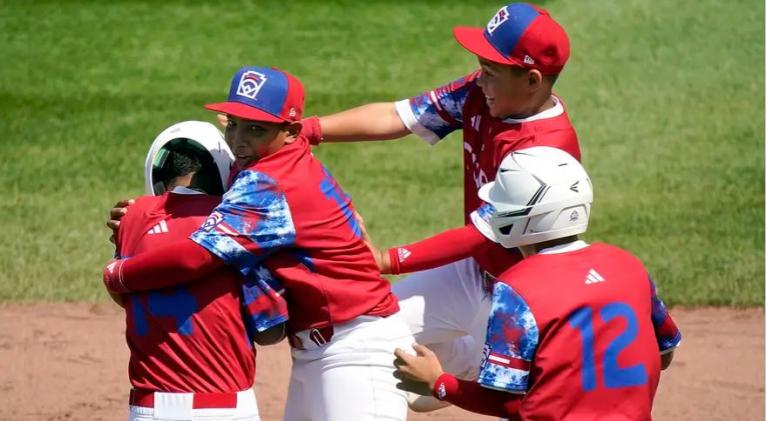 Luis Gurriel (izquierda), de Cuba, es felicitado por Didier Castillo (15), Edgar Torrez y Liusban Sánchez (12) en el juego del sábado 19 de agosto de 2023, ante Australia, en la Serie Mundial de Pequeñas Ligas (AP Foto/Tom E. Puskar)